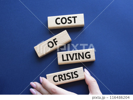 Cost of Living Crisis symbol. Wooden blocks with words Cost of Living Crisis. Businessman hand. Beautiful deep blue background. Business and Cost of Living Crisis. Copy space. Cost of Living Crisis symbol. Wooden blocks with words Cost of Living Crisis. Businessman hand. Beautiful deep blue background. Business and Cost of Living Crisis. Copy space. 116486204