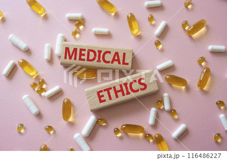 Medical Ethics symbol. Concept word Medical Ethics on wooden blocks. Beautiful pink background with pills. Medicine and Medical Ethics concept. Copy space 116486227