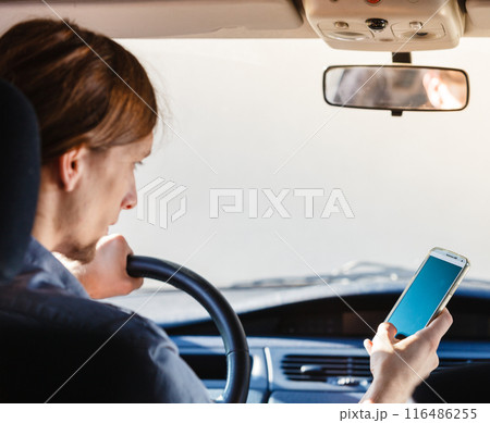 Man using his phone while driving car. 116486255
