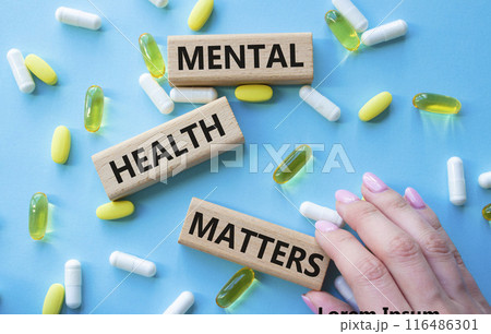 Mental Health Matters symbol. Concept words Mental Health Matters on wooden blocks. Beautiful blue background with pills. Doctor hand. Healthcare and Mental Health Matters concept. Copy space. 116486301