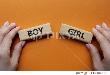 Boy or Girl symbol. Concept word Boy or Girl on wooden blocks. Man hand. Beautiful orange background. Gender and Boy or Girl concept. Copy space 116486359