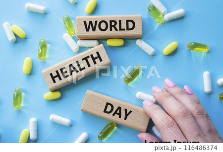 World Health Day symbol. Concept words World Health Day on wooden blocks. Beautiful blue background with pills. Doctor hand. Healthcare and World Health Day concept. Copy space. 116486374