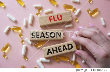 Flu Season Ahead symbol. Concept word Flu Season Ahead on wooden blocks. Doctor hand. Beautiful pink background with pills. Medicine and Flu Season Ahead concept. Copy space 116486375