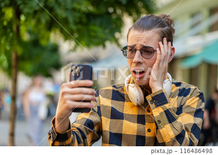 Shocked sad angry young man using smartphone receive email message bad news, fail, loses, loss, fail Shocked sad angry young man using smartphone receive email message bad news, fail, loses, loss, fail 116486498