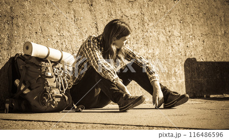 Man tourist backpacker sitting by grunge wall outdoor Man tourist backpacker sitting by grunge wall outdoor 116486596
