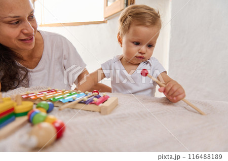 Mother and baby playing with colorful xylophone at home, developing musical skills and bonding 116488189