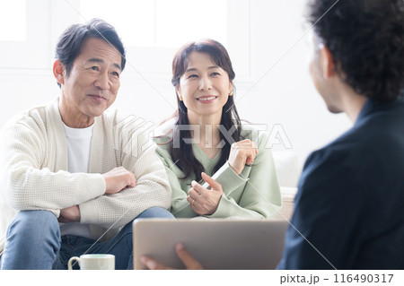 営業マンの説明を受ける笑顔の50代夫婦　投資や保険、不動産など　笑顔でクローズアップ 116490317