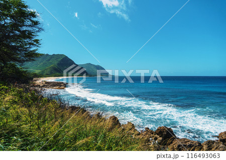 A beautiful scenic view of a cliff by the ocean with a mountain in the distance A beautiful scenic view of a cliff by the ocean with a mountain in the distance 116493063