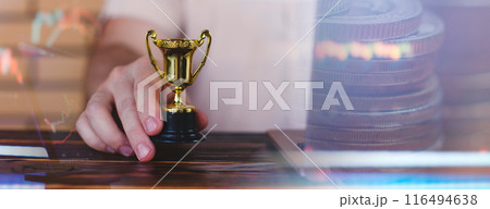 Businessman is using a laptop and holding a golden trophy. Finding the best investment and saving money 116494638