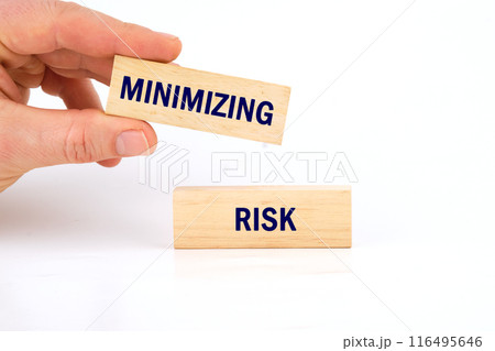 MINIMIZING RISK word written on wooden blocks with a man's hand on a white background 116495646