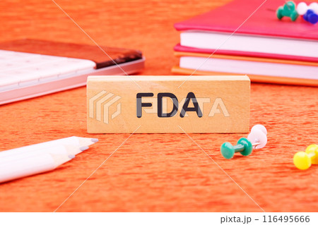 FDA Food Drug Administration symbol on wooden blocks in front of an orange background 116495666