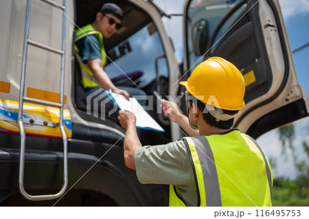 A man in a yellow vest is standing next to a truck and talking to another man A man in a yellow vest is standing next to a truck and talking to another man 116495753