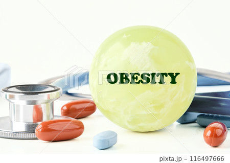 Health Awareness Concept. Obesity word written on a balloon in a composition with a stethoscope, pills and vitamins on a white background Health Awareness Concept. Obesity word written on a balloon in a composition with a stethoscope, pills and vitamins on a white background 116497666