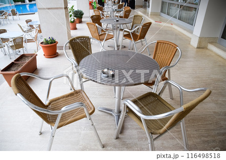 Metal tables and chairs with wicker seats in outdoor cafe. 116498518