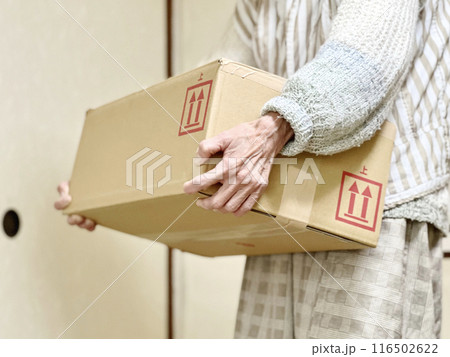 ダンボールを持ち上げる高齢女性の手 116502622