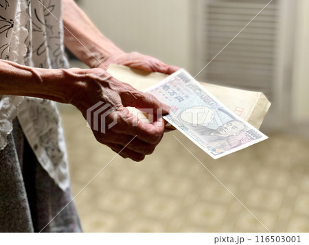 封筒と1万円札を持つ高齢女性の手元 116503001