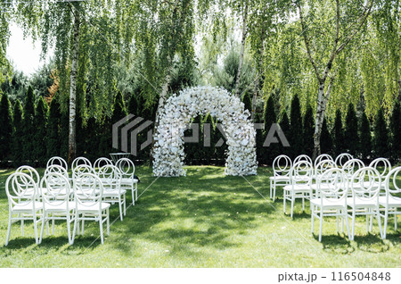 Wedding ceremony. Very beautiful and stylish wedding arch, decorated with various fresh flowers, standing in the garden. 116504848