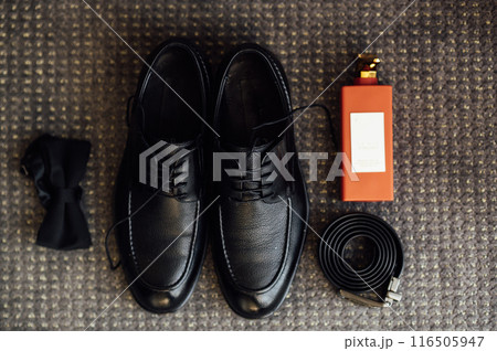 Groom's wedding details. Watch, rings and belt placed on a checkered jacket 116505947