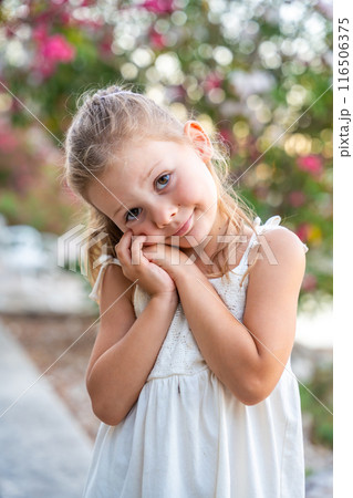 Portrait of little girl in white dress happy smiling on blooming park background in Croatia Portrait of little girl in white dress happy smiling on blooming park background in Croatia 116506375