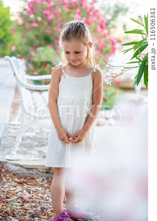 Portrait of little girl in white dress happy smiling on blooming park background in Croatia Portrait of little girl in white dress happy smiling on blooming park background in Croatia 116506381