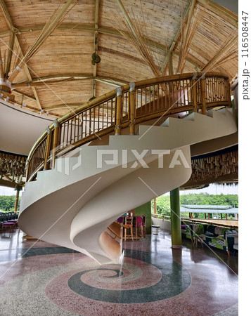 There is a spiral staircase in a building with a wooden railing 116508447