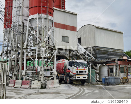 A concrete mixer truck is stationary outside of a concrete factory 116508449