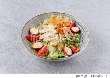 Caesar salad with chicken and bacon on a gray background on a plate for a restaurant menu 116509223