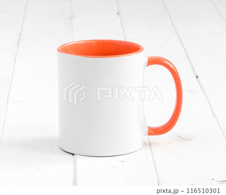 white cup with dark orange inside on a table 116510301