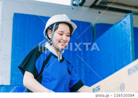 トラックの荷台に乗るヘルメット姿の女性ドライバー 116510384