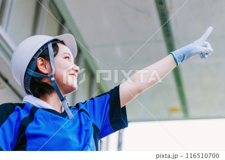 トラックの荷台で指を差すヘルメット姿の女性ドライバー トラックの荷台で指を差すヘルメット姿の女性ドライバー 116510700