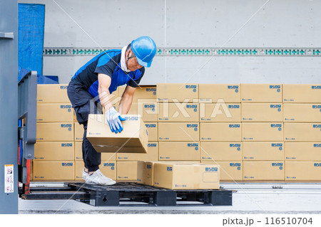 トラックからフォークリフトで荷物を下ろすヘルメット姿の男性 トラックからフォークリフトで荷物を下ろすヘルメット姿の男性 116510704