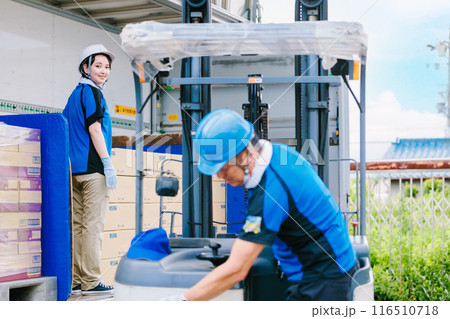 トラックにフォークリフトで荷物を積むヘルメット姿の作業員 116510718