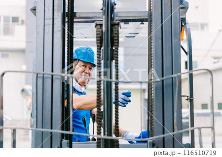 フォークリフトを操縦するヘルメット姿の男性 116510719