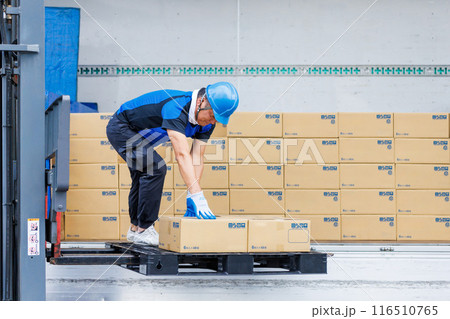 トラックからフォークリフトで荷物を下ろすヘルメット姿の男性 トラックからフォークリフトで荷物を下ろすヘルメット姿の男性 116510765