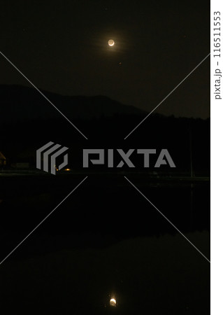 北杜市白州町、代掻き済んで田植え待つ田に映す皐月の夕暮れに浮かぶ三日月 116511553