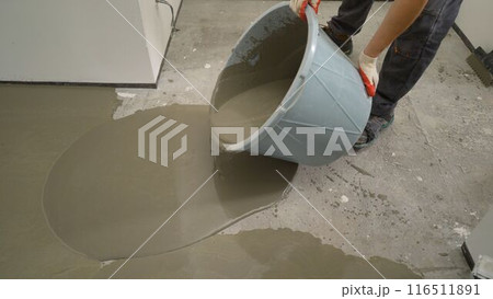 The self-leveling floor solution is poured onto the floor. A worker pours self-leveling solution to level the floor. Self-leveling floor. Floor leveling solution. The self-leveling floor solution is poured onto the floor. A worker pours self-leveling solution to level the floor. Self-leveling floor. Floor leveling solution. 116511891