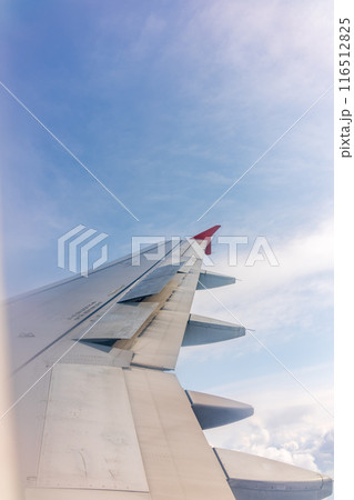 View from the airplane window at a beautiful cloudy sky and the airplane wing View from the airplane window at a beautiful cloudy sky and the airplane wing 116512825