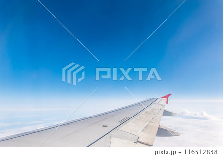 View from the airplane window at a beautiful cloudy sky and the airplane wing View from the airplane window at a beautiful cloudy sky and the airplane wing 116512838
