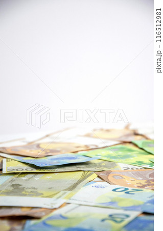 A close-up image of euro banknotes scattered on a white background A close-up image of euro banknotes scattered on a white background 116512981