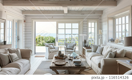 Interior of a living room with white walls, sofa and cushions. Sitting room in coastal cottage with sea view. Luxury lounge room 116514326