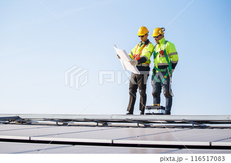 Professional electric engineers survey and inspect solar panels installation on the factory metal sheet roof top, electric engineer team inspecting and check solar cell system. Professional electric engineers survey and inspect solar panels installation on the factory metal sheet roof top, electric engineer team inspecting and check solar cell system. 116517083