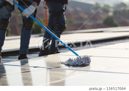 Professional electrical engineers working on the residential rooftop to clean up the dusty solar panels. 116517084