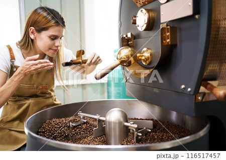 Professional coffee roaster working with modern automated roasting machine in the coffee roasting factory. Food and beverage business concept. 116517457