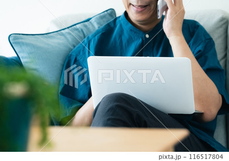 ソファでスマホ通話するミドル男性 116517804