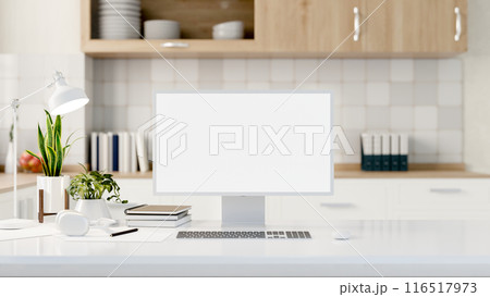 A computer with a white-screen mockup on a white table with a blurred background of a modern kitchen 116517973