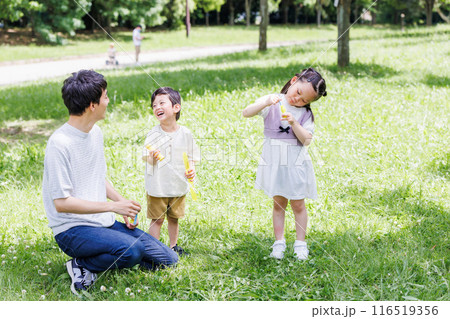 新緑の公園でシャボン玉遊びをする親子 116519356