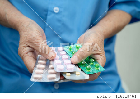 Senior Asian woman holding capsule pills drug in blister packaging for treatment infection patient in hospital. Senior Asian woman holding capsule pills drug in blister packaging for treatment infection patient in hospital. 116519461