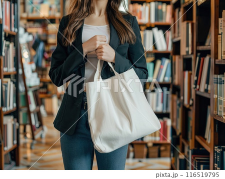 Mockup woman holding a blank white tote bag standing in a library with bookshelf Generative AI 116519795