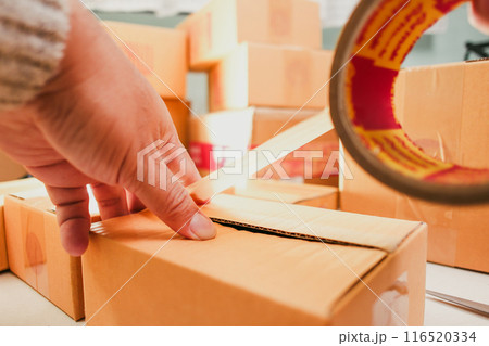 Goods delivery concept , Human hand packs merchandise into cardboard box for delivery to a customer Goods delivery concept , Human hand packs merchandise into cardboard box for delivery to a customer 116520334