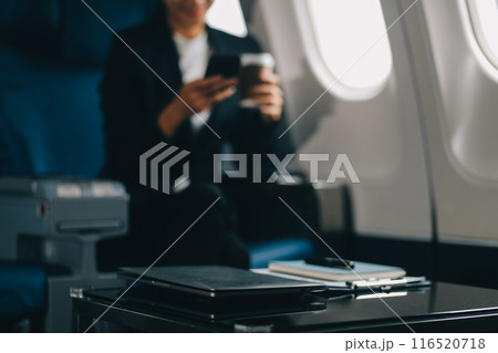 Young business woman sitting inside plane at the airport with sky view from the window drinking a cup of coffee 116520718